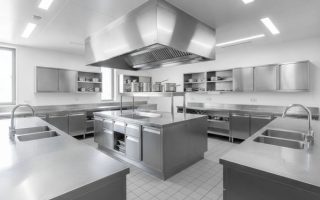 Cozinha industrial equipada com bancadas, pias e armários de aço inox para adequação sanitária