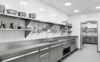 Cozinha hospitalar equipada com bancadas, pias e armários de aço inox organizados em ambiente limpo e iluminado