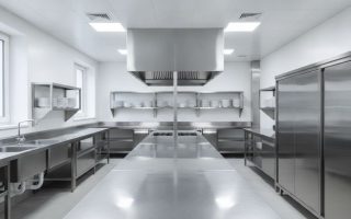 Cozinha industrial reformada com bancadas, pias, prateleiras e coifas em aço inox organizadas por zonas de trabalho
