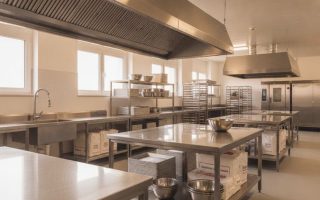 Cozinha para padaria industrial equipada com bancadas, prateleiras e coifa em aço inox