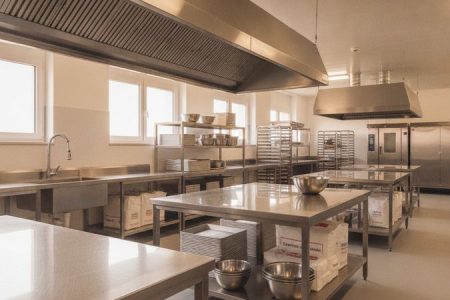 Cozinha para padaria industrial equipada com bancadas, prateleiras e coifa em aço inox