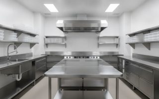 Cozinha industrial em aço inox equipada como dark kitchen com bancadas, coifa, prateleiras e pia industrial