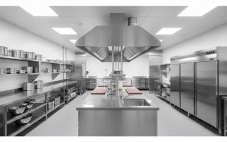 Cozinha industrial equipada com bancadas, coifa, prateleiras e balcão refrigerado em aço inox